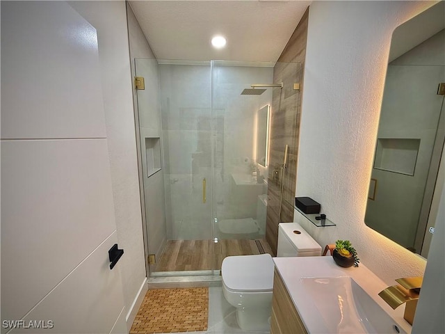 bathroom featuring a shower stall, toilet, recessed lighting, a textured wall, and vanity