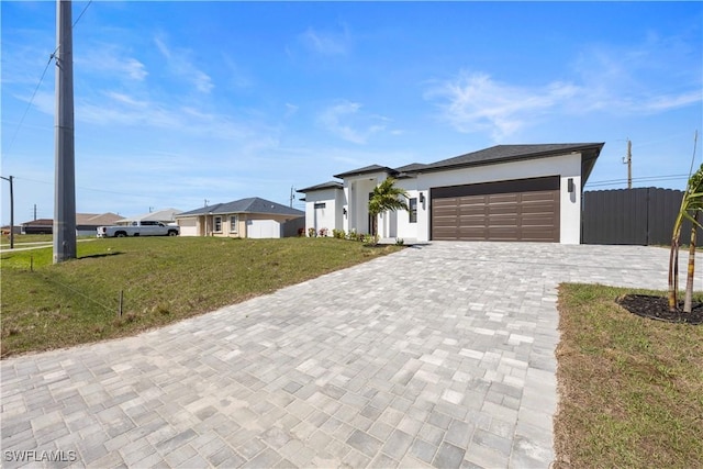 view of front of house with fence, a front yard, stucco siding, decorative driveway, and an attached garage