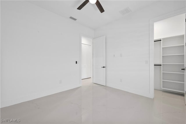 unfurnished bedroom with visible vents, baseboards, a walk in closet, and a ceiling fan