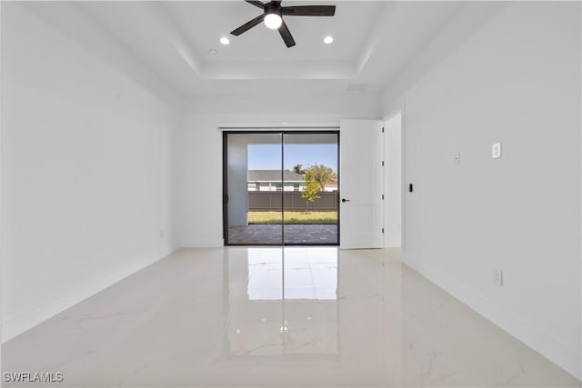 spare room featuring baseboards, a tray ceiling, recessed lighting, marble finish floor, and a ceiling fan