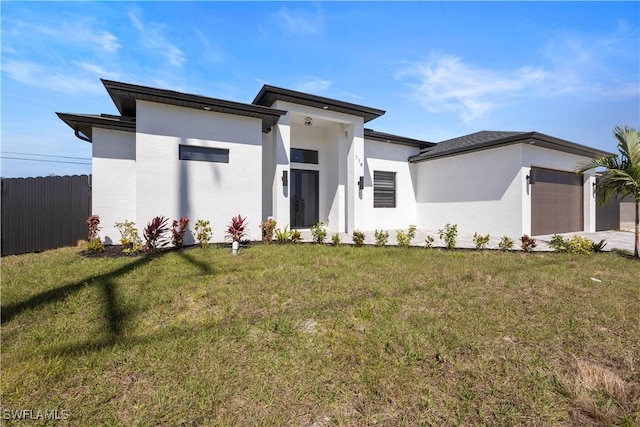 prairie-style home with a garage, stucco siding, a front yard, and fence