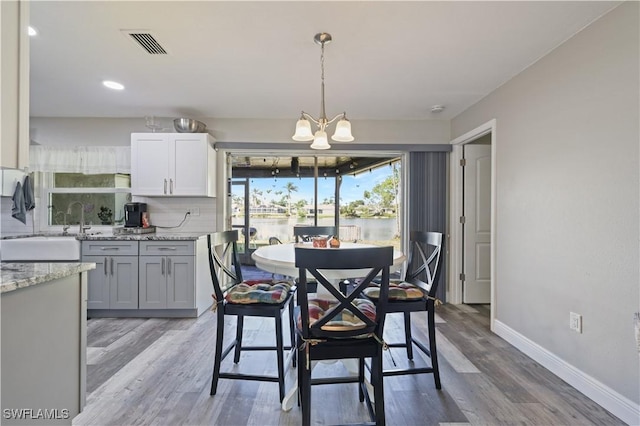 dining space featuring visible vents, baseboards, light wood-type flooring, recessed lighting, and an inviting chandelier