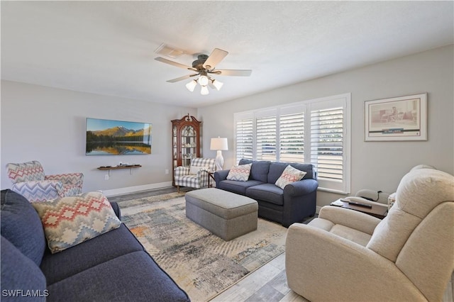 living room with wood finished floors, a ceiling fan, visible vents, and baseboards