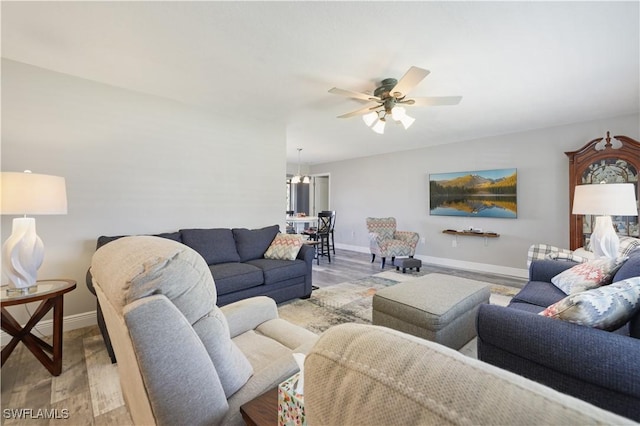 living room featuring ceiling fan, baseboards, and wood finished floors