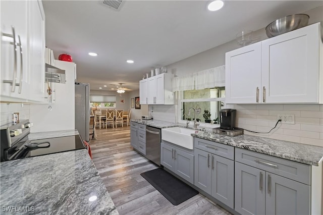 kitchen with visible vents, light wood-style flooring, a sink, stainless steel appliances, and white cabinets