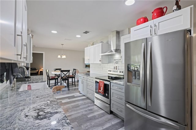 kitchen with visible vents, a sink, light wood-style floors, appliances with stainless steel finishes, and wall chimney exhaust hood