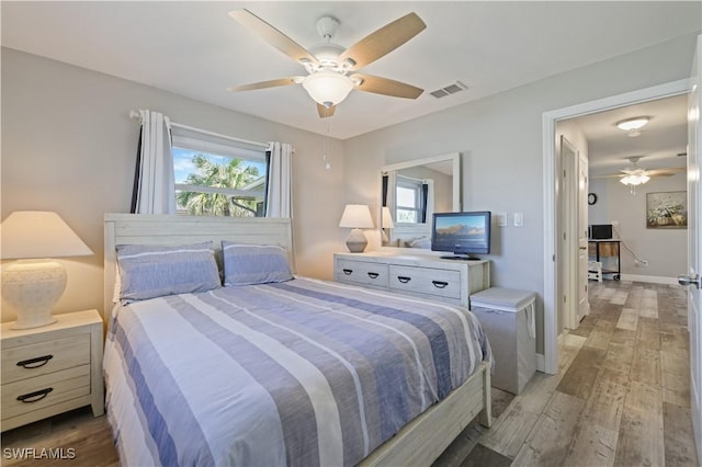 bedroom with light wood-type flooring, visible vents, baseboards, and a ceiling fan