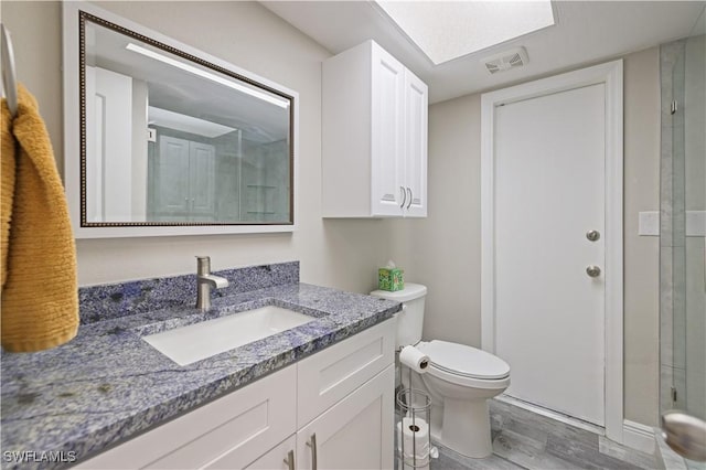 bathroom with visible vents, toilet, wood finished floors, an enclosed shower, and vanity