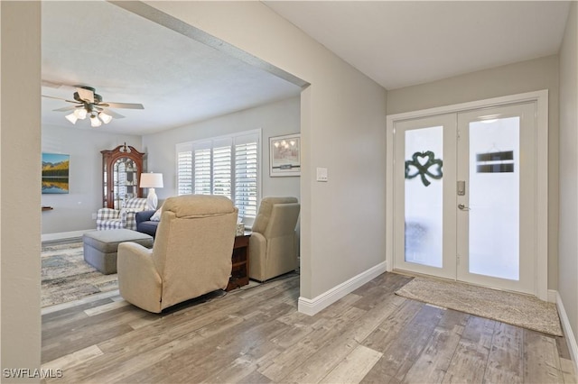 foyer featuring light wood-type flooring, baseboards, ceiling fan, and french doors