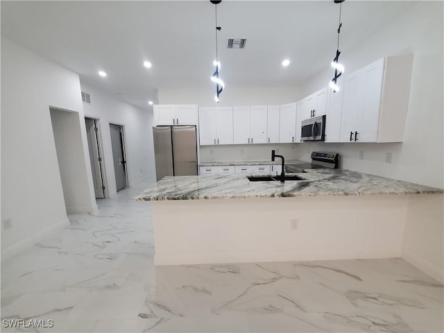 kitchen with light stone counters, visible vents, a peninsula, a sink, and stainless steel appliances