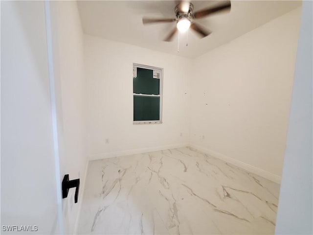 spare room featuring marble finish floor, a ceiling fan, and baseboards