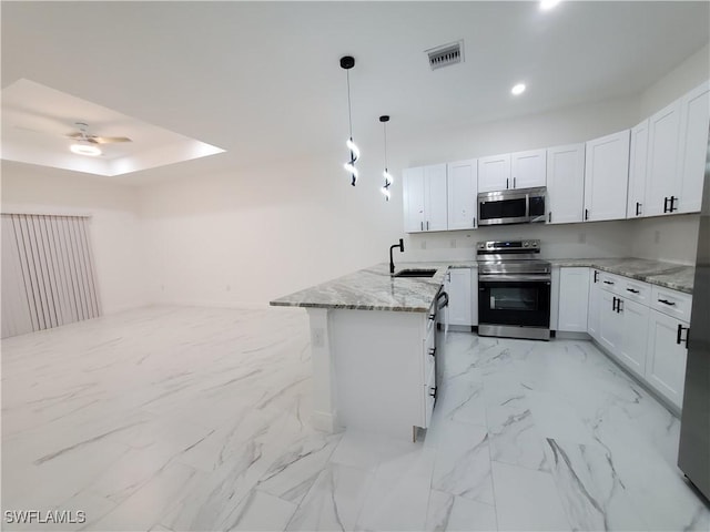 kitchen with light stone counters, a peninsula, stainless steel appliances, white cabinetry, and a sink