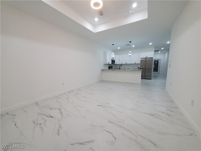 unfurnished living room with marble finish floor, a sink, a tray ceiling, recessed lighting, and baseboards