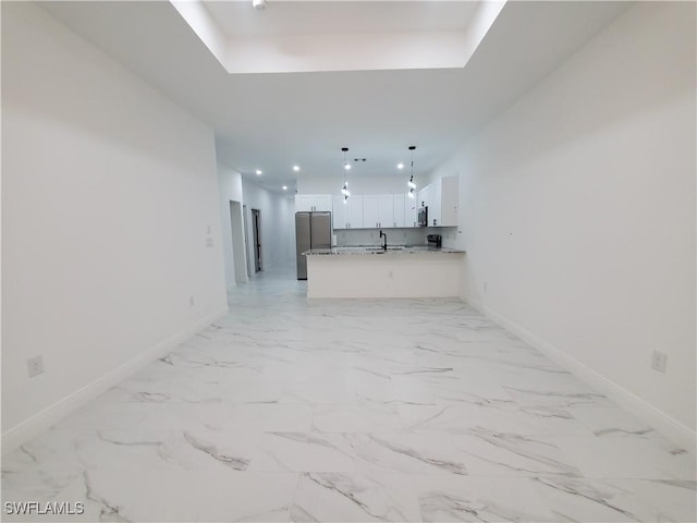 kitchen with open floor plan, white cabinets, freestanding refrigerator, and baseboards