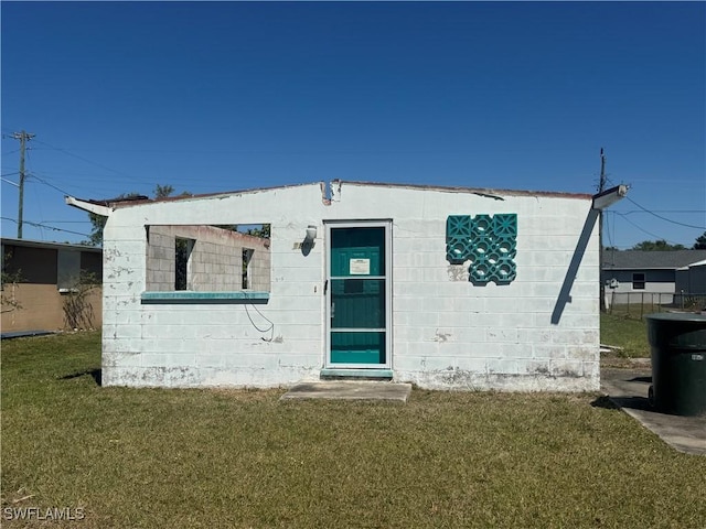 rear view of property featuring concrete block siding and a yard