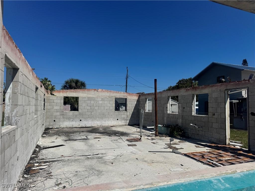 rear view of house with a patio area, concrete block siding, and fence