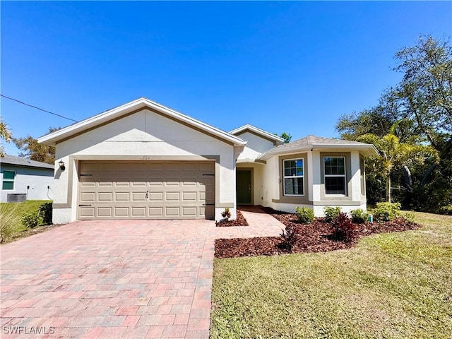 ranch-style house with a front yard, decorative driveway, an attached garage, and stucco siding