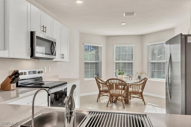 kitchen with light countertops, white cabinets, visible vents, and stainless steel appliances