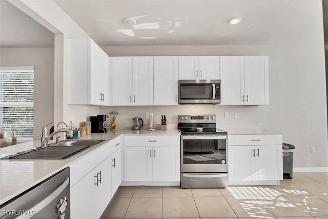 kitchen with a sink, stainless steel appliances, white cabinets, light countertops, and light tile patterned floors