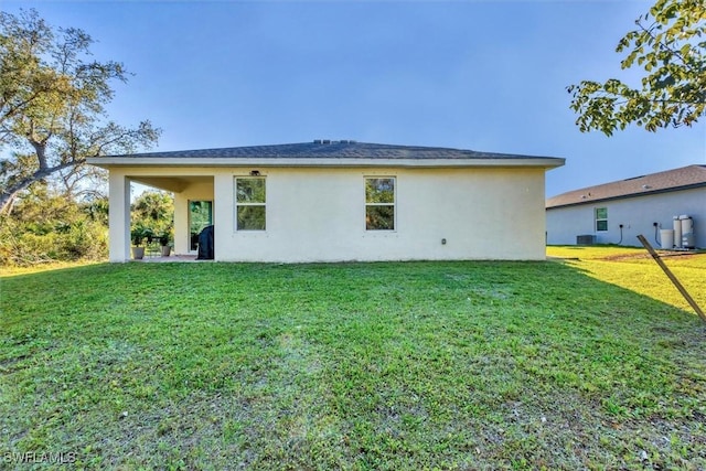 back of house featuring stucco siding and a yard