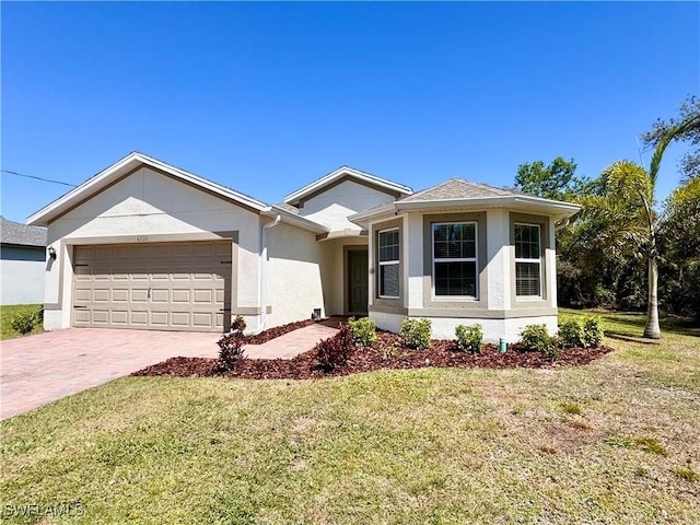 view of front of property featuring a front yard, decorative driveway, an attached garage, and stucco siding