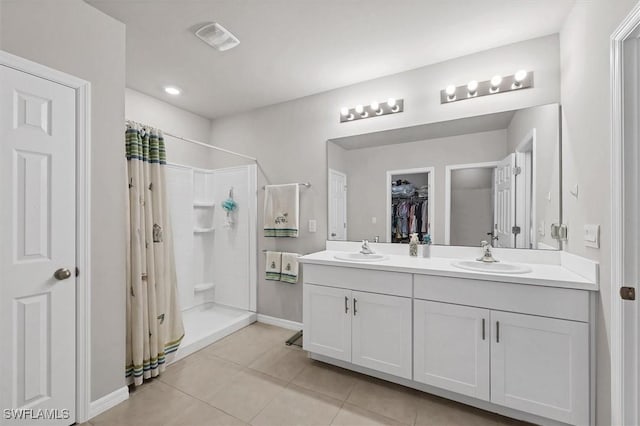 full bath with a sink, a shower stall, tile patterned floors, and double vanity