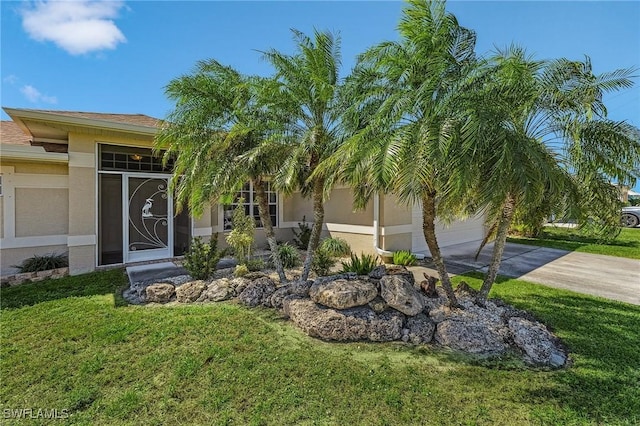 doorway to property with stucco siding, driveway, an attached garage, and a lawn