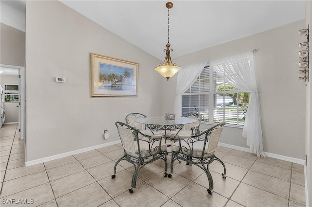 dining area with light tile patterned floors, baseboards, and lofted ceiling