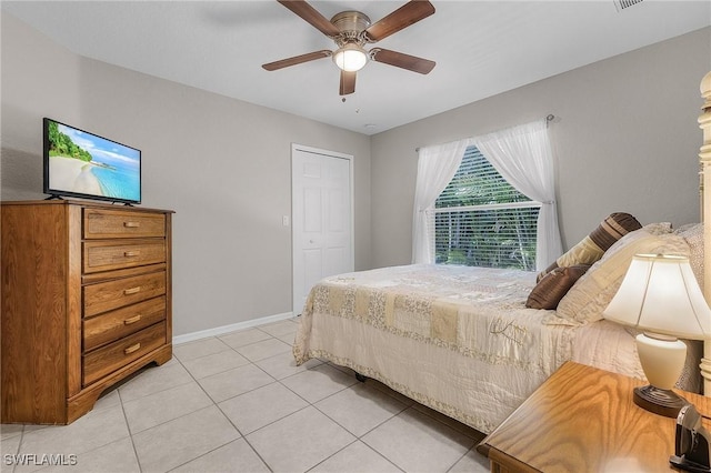 bedroom featuring light tile patterned floors, a closet, baseboards, and a ceiling fan