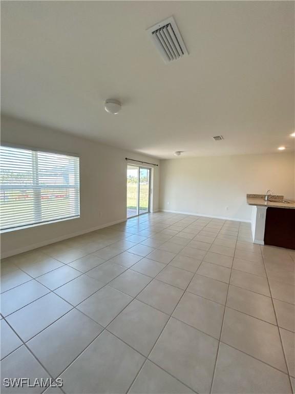 empty room featuring light tile patterned floors, visible vents, and baseboards