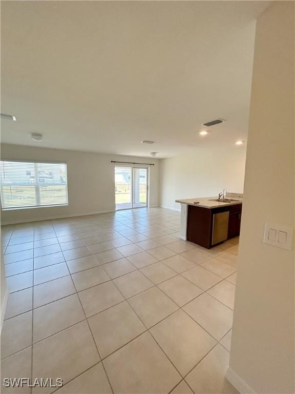 unfurnished room featuring light tile patterned floors, visible vents, baseboards, and a sink