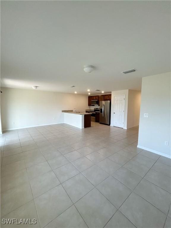 unfurnished living room featuring light tile patterned floors, visible vents, and baseboards