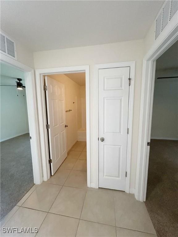 hallway with light tile patterned flooring, visible vents, and light carpet