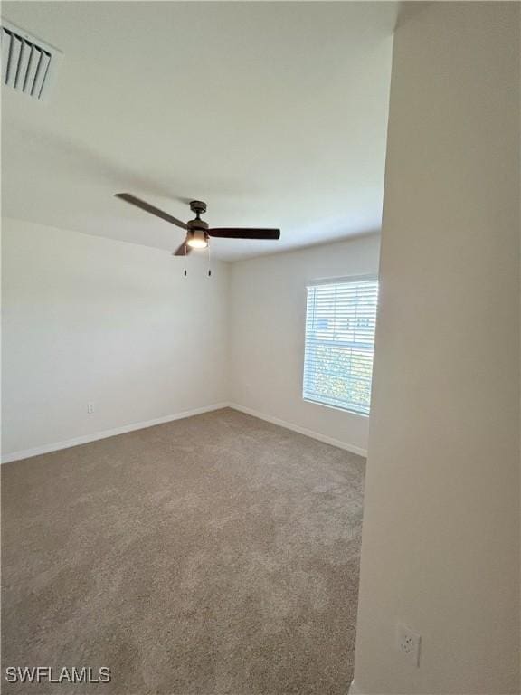 carpeted spare room featuring visible vents, baseboards, and a ceiling fan