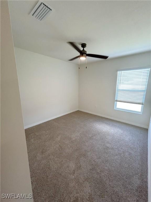 carpeted empty room featuring a ceiling fan, visible vents, and baseboards