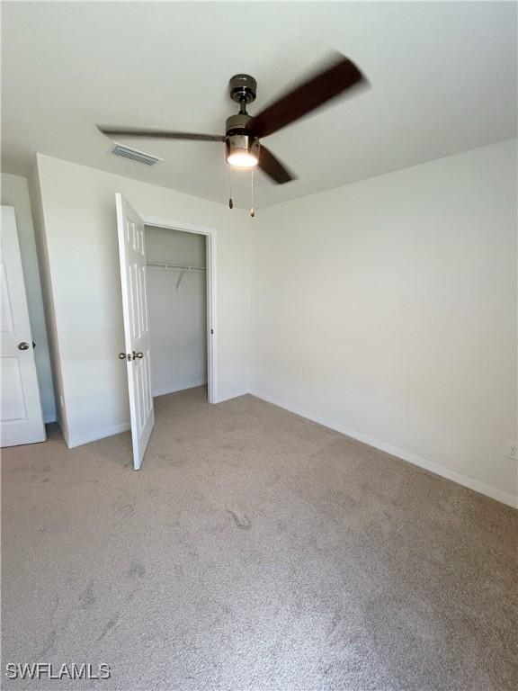 unfurnished bedroom with a ceiling fan, visible vents, baseboards, a closet, and light colored carpet