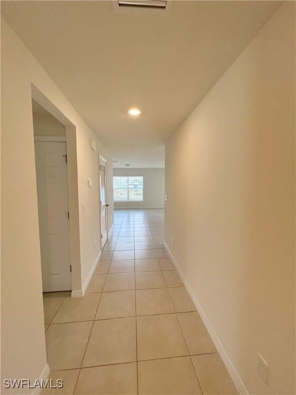 corridor with light tile patterned flooring and baseboards