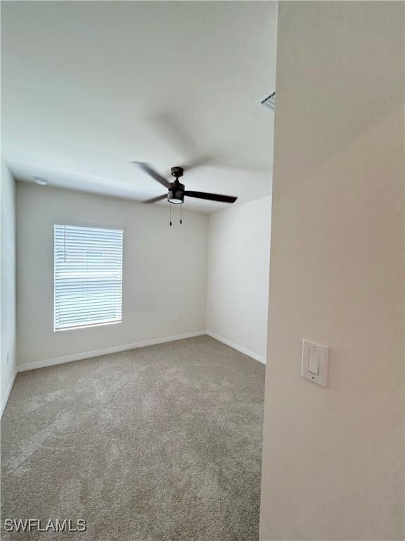 carpeted empty room featuring baseboards and ceiling fan