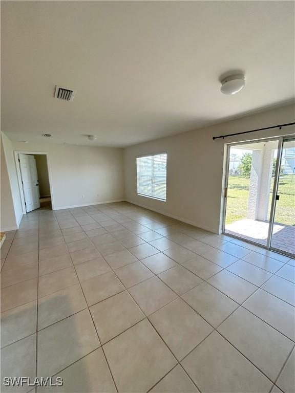 unfurnished room featuring light tile patterned flooring, visible vents, and baseboards