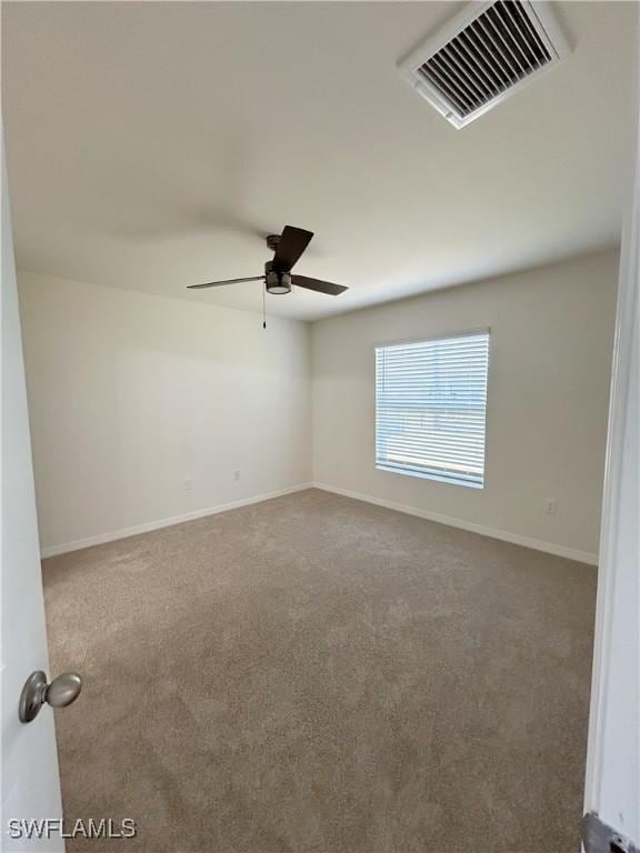 carpeted empty room with baseboards, visible vents, and ceiling fan