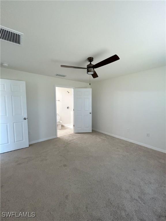 carpeted spare room with visible vents, baseboards, and a ceiling fan