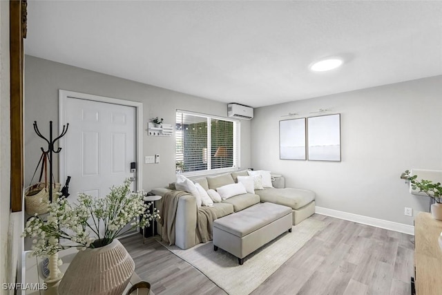 living area with a wall mounted air conditioner, light wood-type flooring, and baseboards