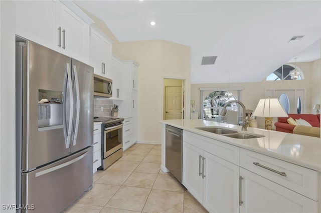 kitchen with tasteful backsplash, light countertops, appliances with stainless steel finishes, light tile patterned flooring, and a sink