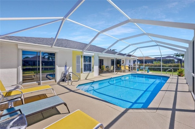 outdoor pool featuring glass enclosure and a patio