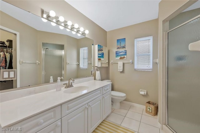 bathroom with tile patterned floors, toilet, a stall shower, baseboards, and vanity