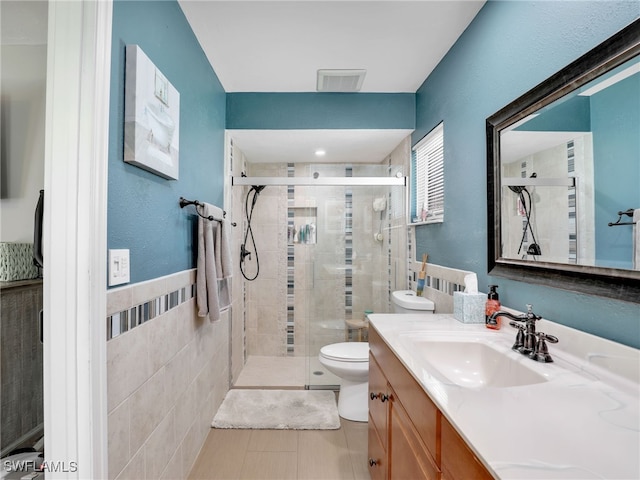 bathroom featuring vanity, visible vents, a stall shower, tile walls, and toilet