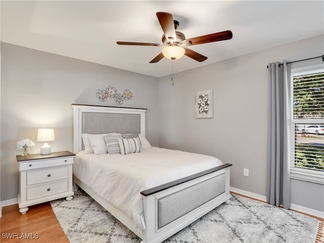 bedroom featuring a ceiling fan, light wood-style floors, and baseboards