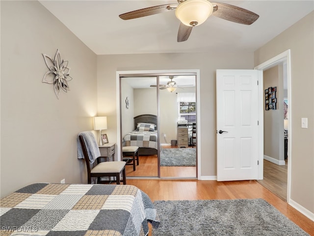 bedroom featuring ceiling fan, a closet, baseboards, and wood finished floors