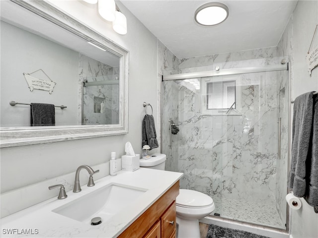 bathroom featuring a marble finish shower, toilet, and vanity