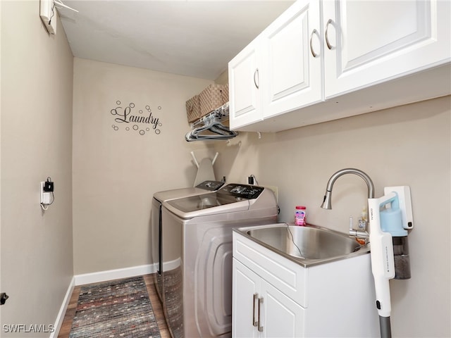 washroom featuring dark wood-type flooring, baseboards, washer and clothes dryer, cabinet space, and a sink